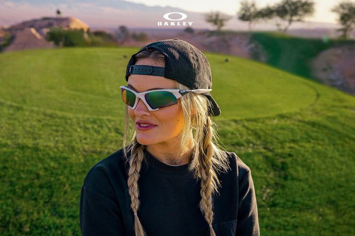 Woman wearing Oakley Suture Jacket sunglasses on a golf course at sunset