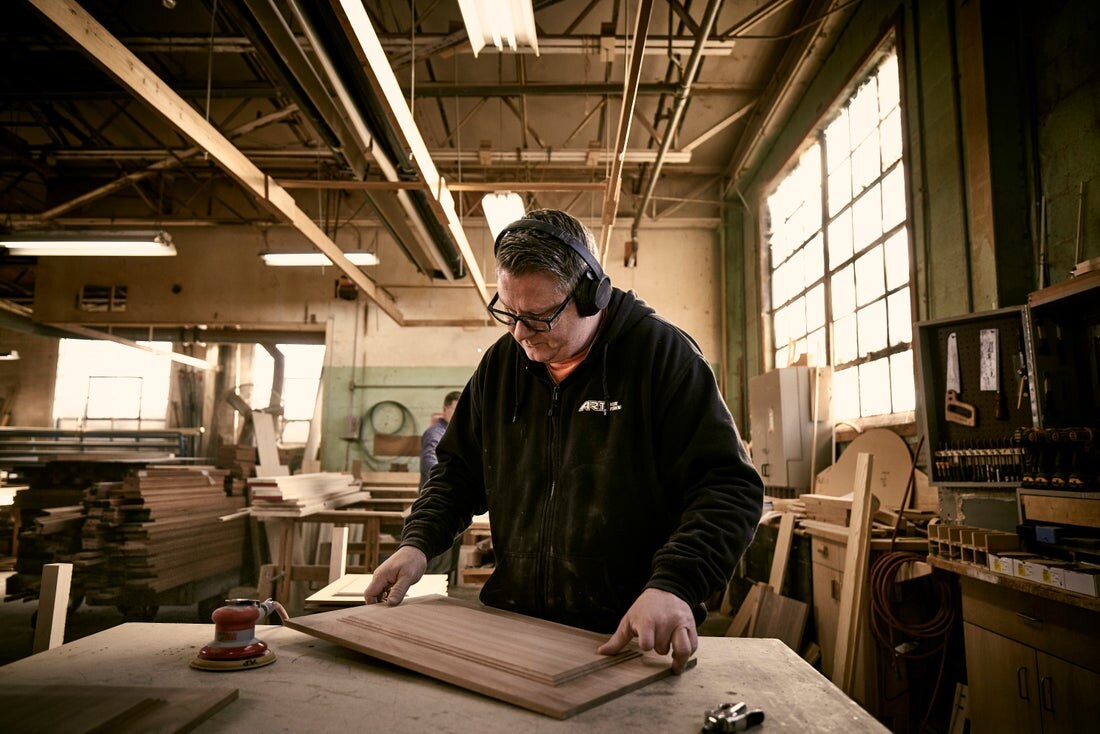 Woodworker at a bench in a home workshop wearing safety glasses