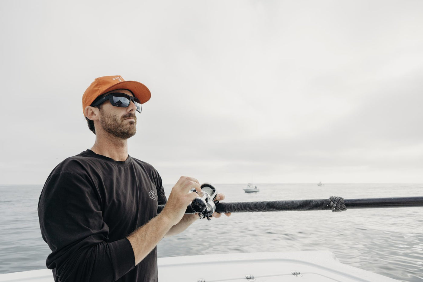 Angler on the water wearing polarized sunglasses while working a fishing reel